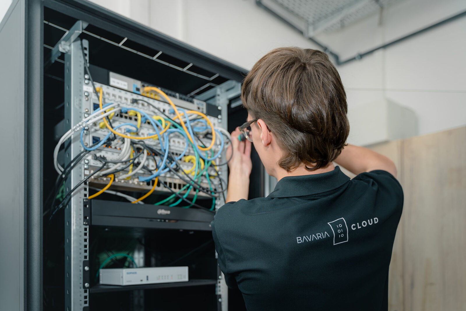 Phishing erkennen im Mittelstand: So schützen sich Unternehmen wirklich 2 BavariaCloud-Technikerin arbeitet am Netzwerkschrank mit Firewall-Appliance