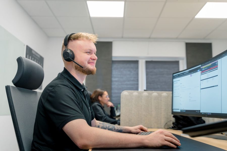 Bavariacloud Mitarbeiter mit Headset sitzt am Schreibtisch beim Helpdesk, Service Desk, IT-Support