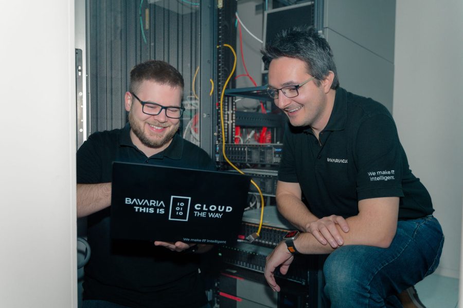 Zwei BavariaCloud-Mitarbeiter prüfen gemeinsam eine E-Mail am Laptop vor einem Serverschrank